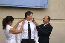 Nina and Dad putting shoulder insignias on Ensign Matt Paddock during commissioning ceremony